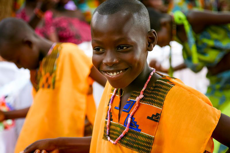 A child smiles in a birght orange outfit