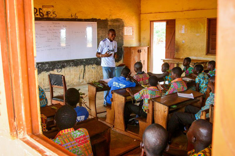 Children sit in a classroom and listen to their teacher