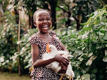 A child holding a chicken that was giving through Compassion's gift catalog.