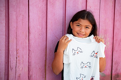 Odalis smiles while holding the shirt she received as a Christmas gift.