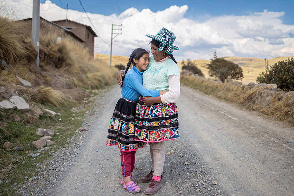 a girl hugs her mother while standing on a gravel path
