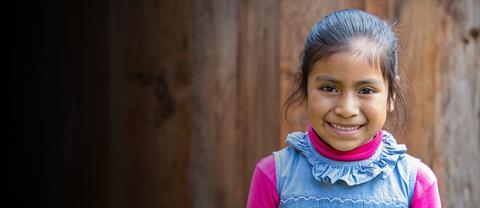 Girl smiling in front of a wooden wall