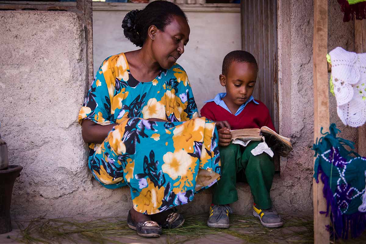 A young boy reading to his mom