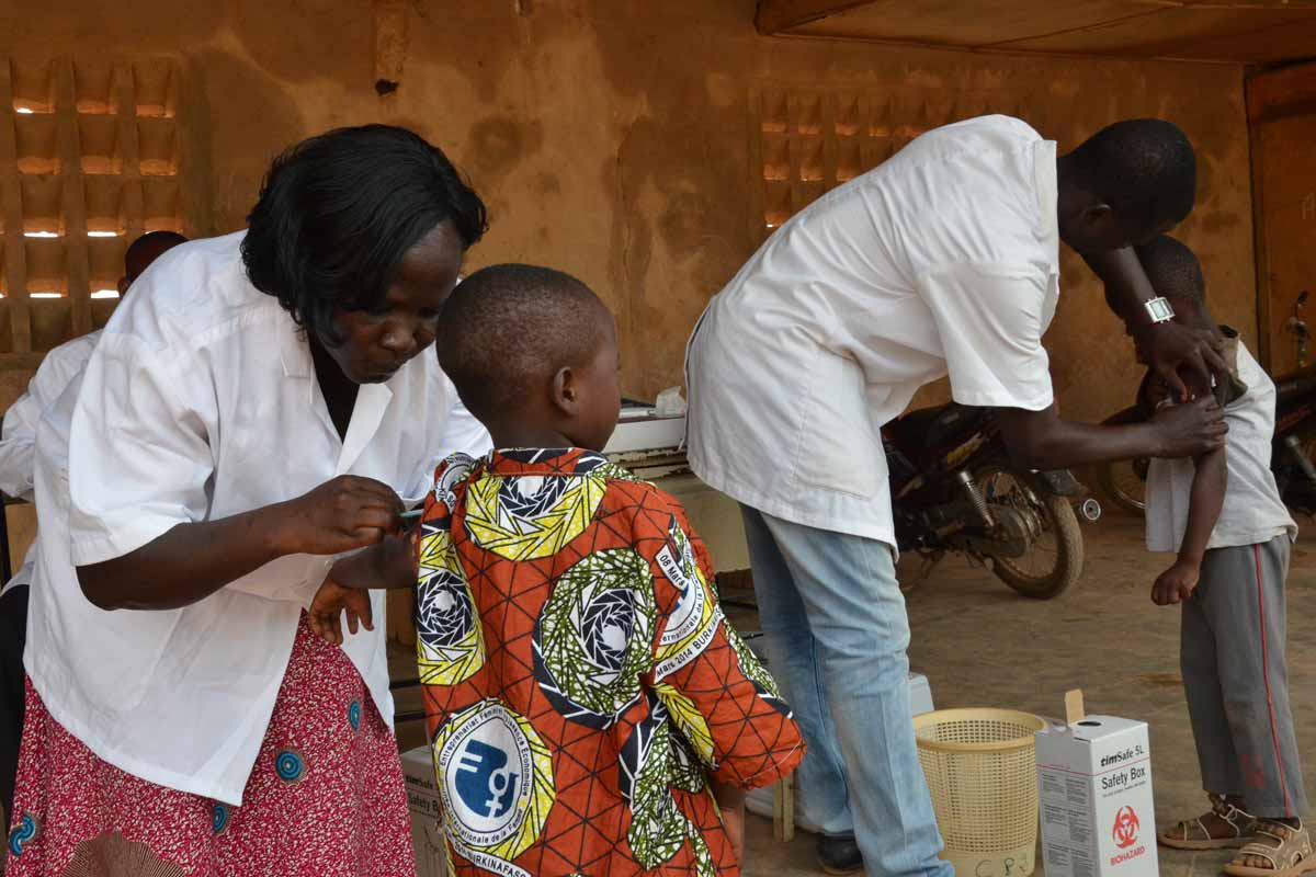 Boys in Burkina Faso receiving vaccinations from medical professionals