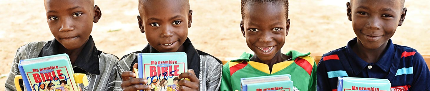 Four children holding Bibles they received from Compassion
