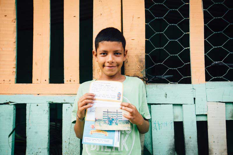 A boy holds a letter from his sponsor
