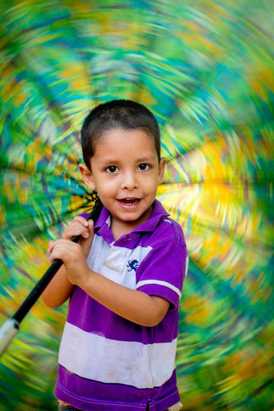 A boy spins a colorful umbrella behind his head