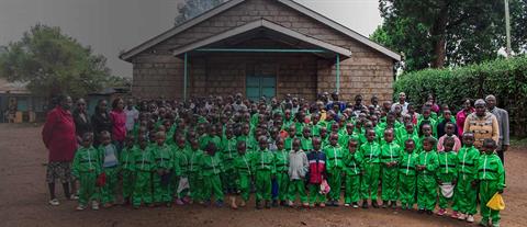 A large group of children assembled in rows in front of a building