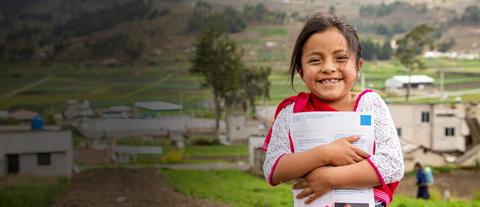 A smiling girl holding a letter from her sponsor