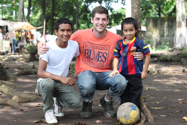A young man smiles with two children