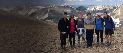 A group of interns on a mountaintop with areas of snow