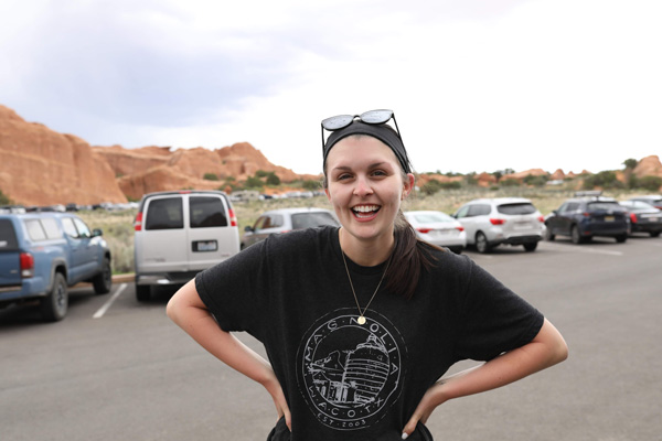 A young lady smiles with red rocks behind her