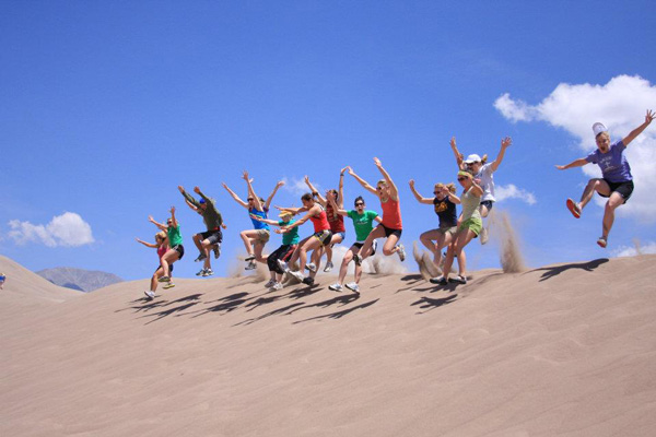 A group of interns run down a sand dune