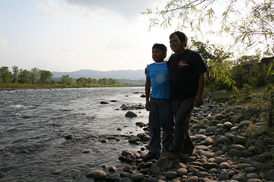 A young boy stands next to a river with his spiritual role model