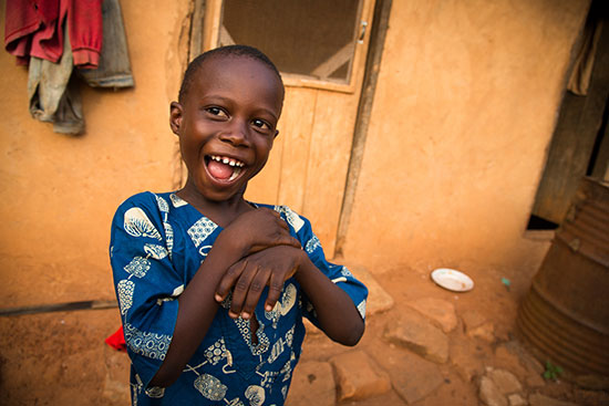 A boy laughing and playing outside his home