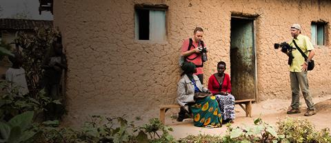 Photographers interact with some beneficiaries in front of a home