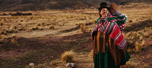 A woman in colorful, traditional Bolivian clothes carrying a baby