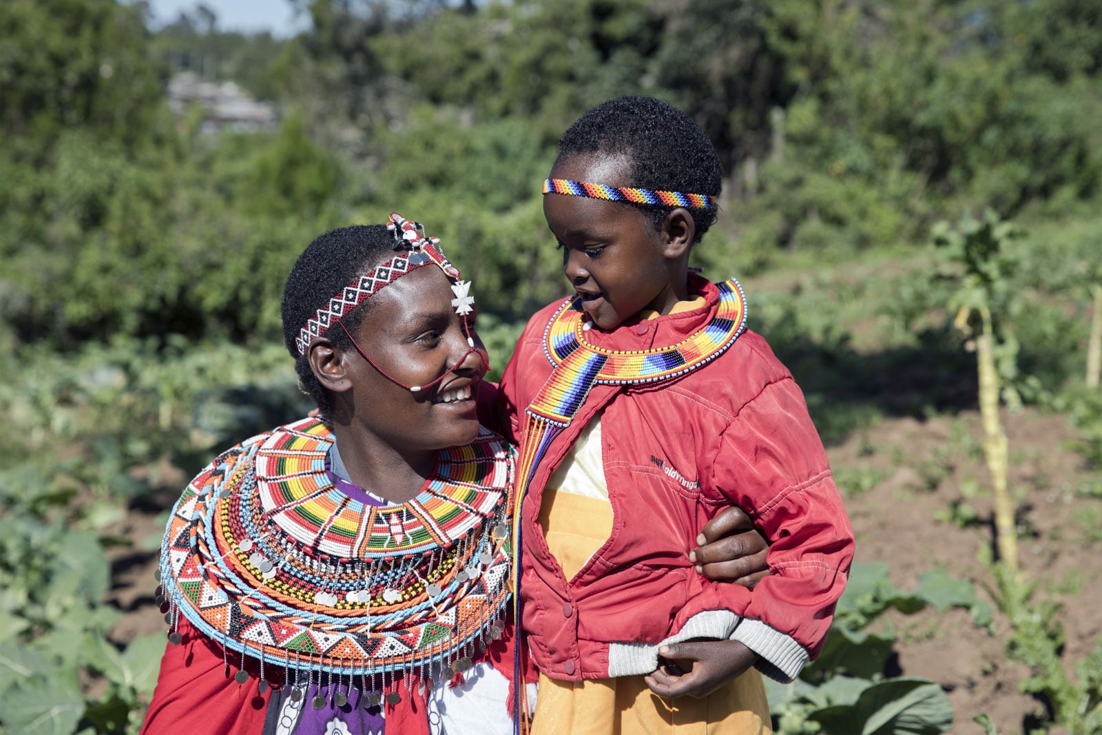 Mother and child hugging while wearing traditional Kenyan clothing.