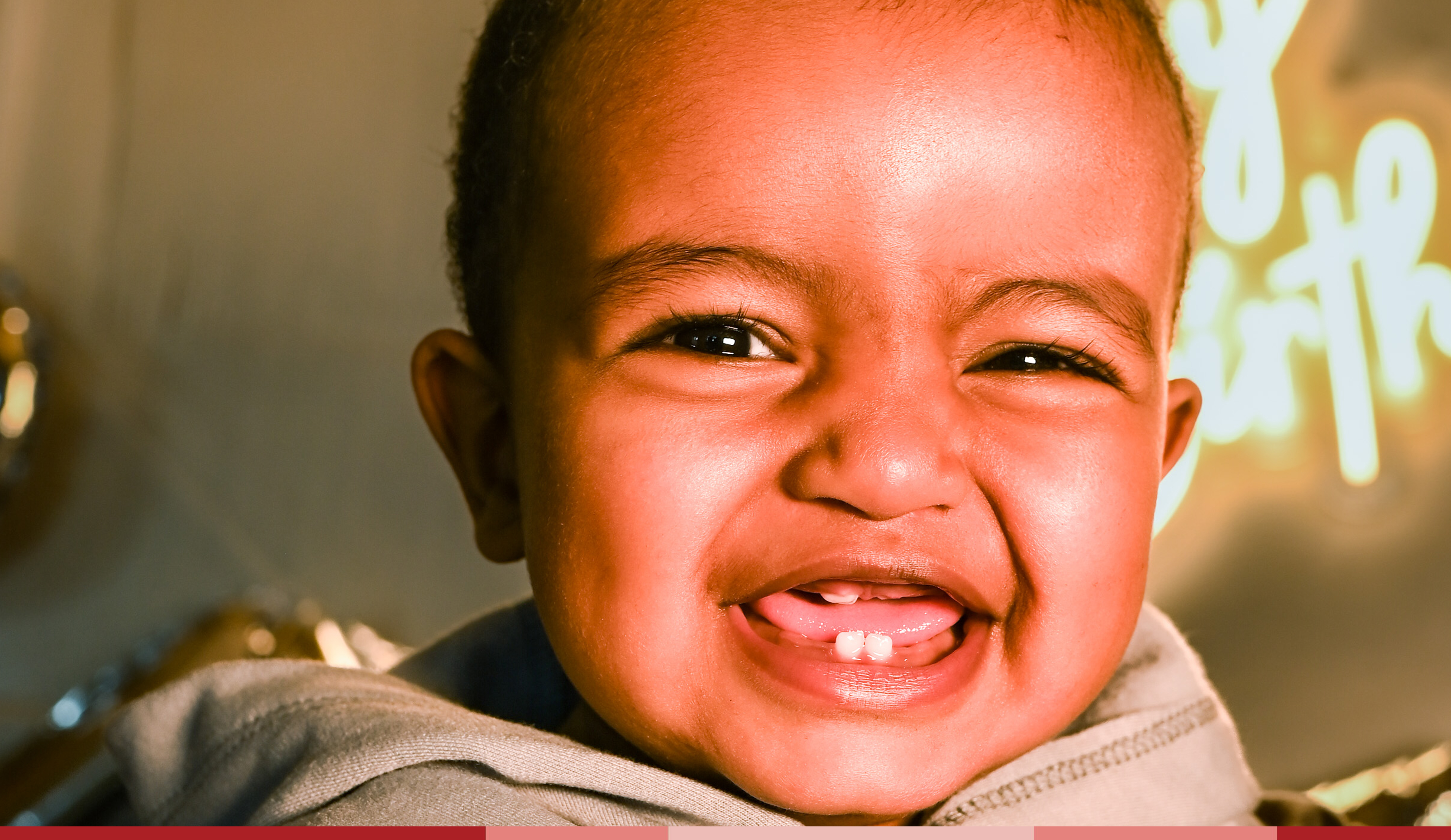 A one year old smiles at the camera at a birthday party