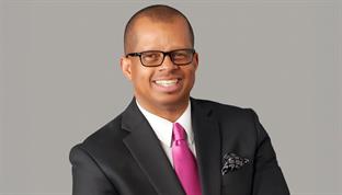 a smiling portrait of Charles Whitaker in front of a gray background