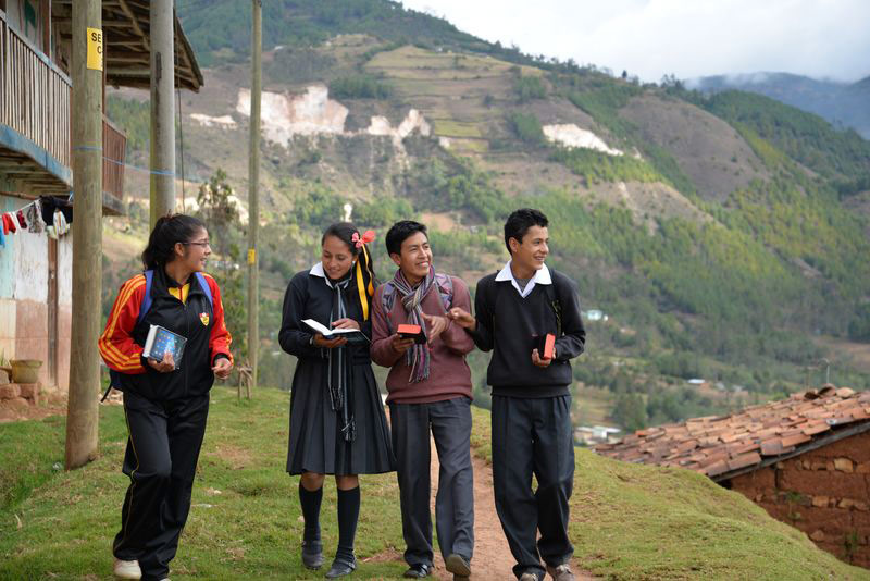 A group of teens walking outside with mountains in the background