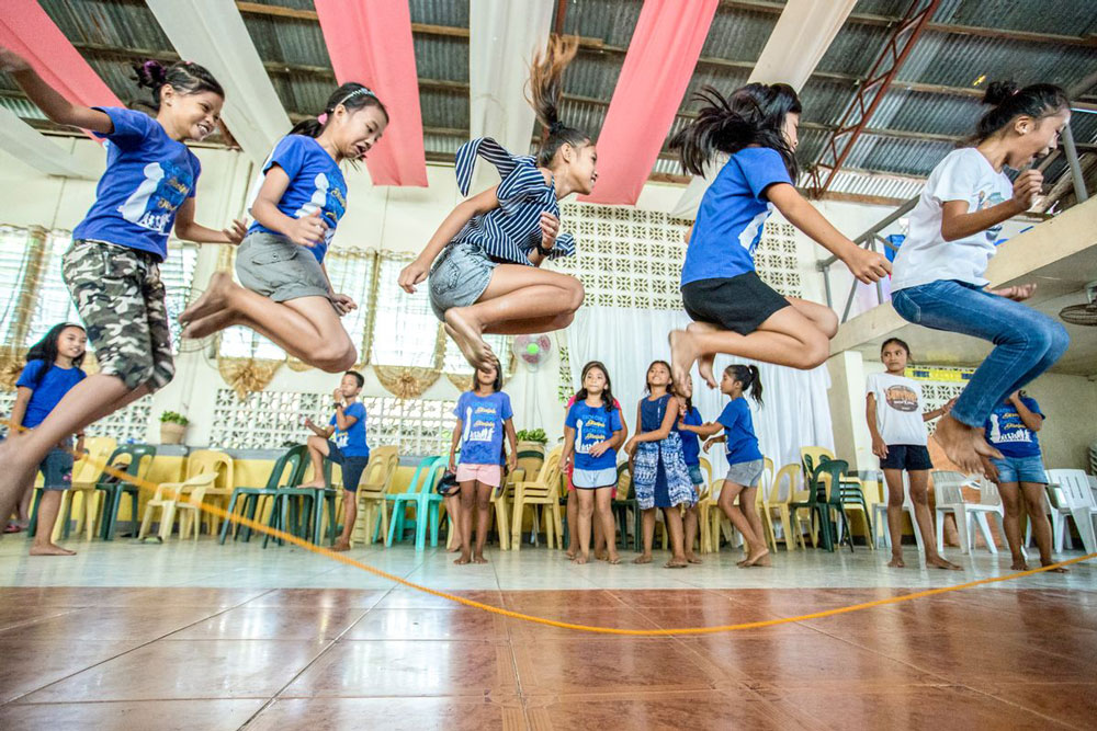 A group of girls play jump rope at their child development center