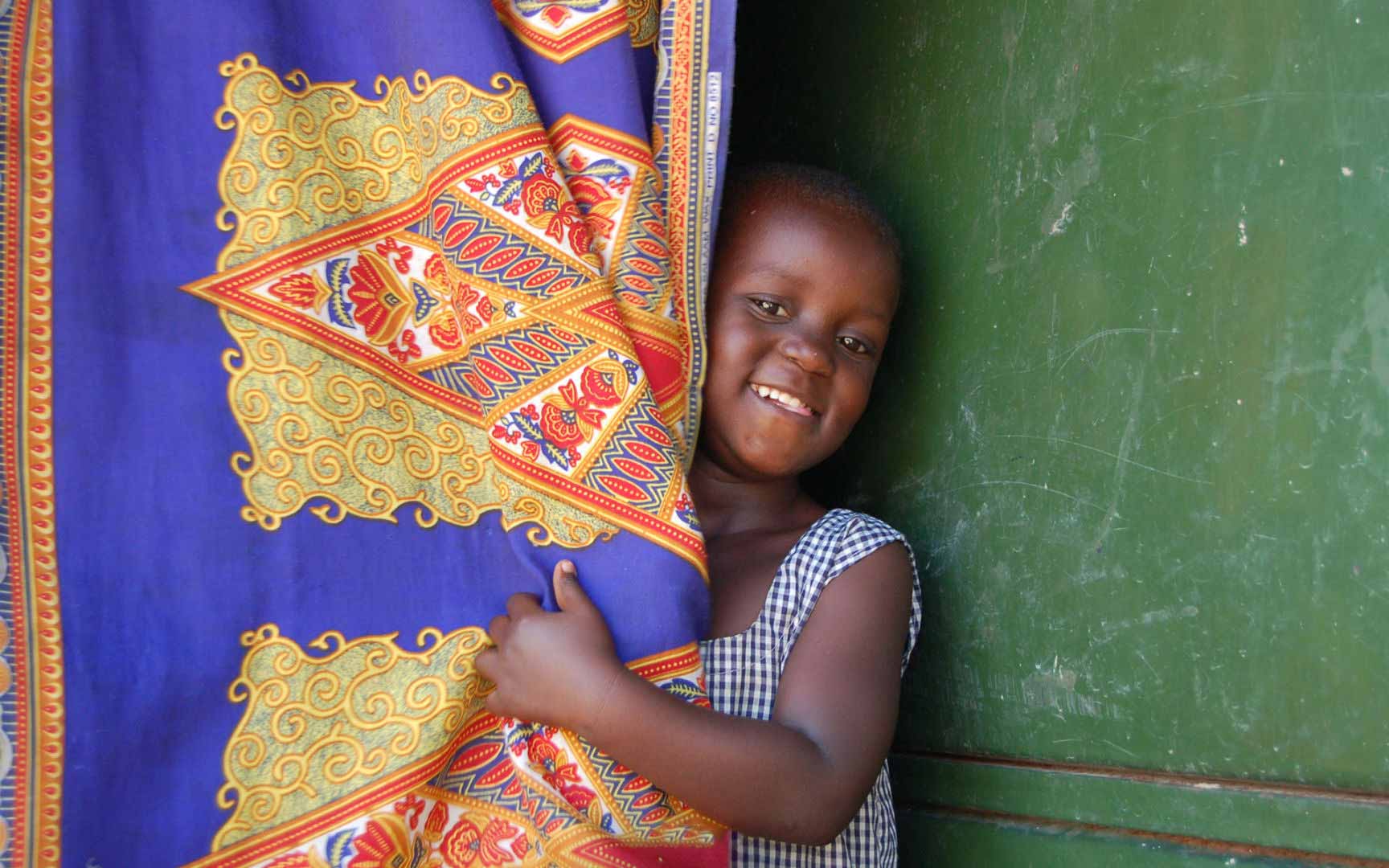 A girl smiling while hiding behind a blanket