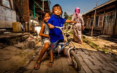 Two children sitting on a bicycle