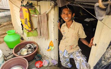 An Indian boy stands in the doorway of his home