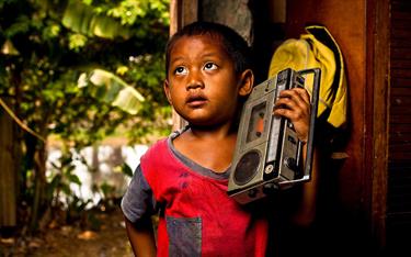 A boy holding a radio against his shoulder
