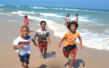 Children running on a beach in Thailand