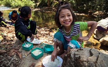 A girl from Myanmar enjoys a meal with rice
