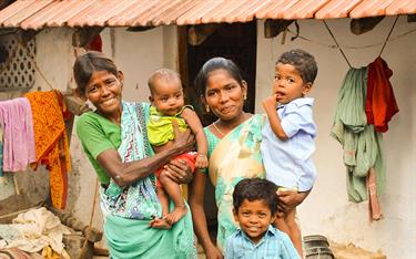 Vennila holds her son while standing with the rest of her family