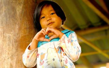 A young girl making the shape of a heart with her hands