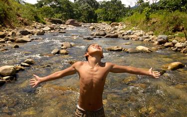 A sponsored boy cools off in a river near his family’s home in Ecuador