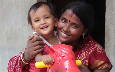 A mother plays with her daughter outside their home in India