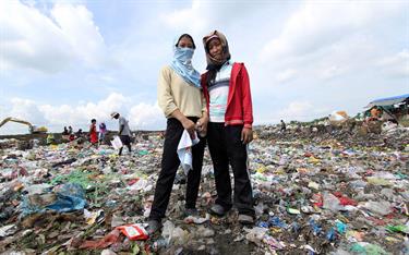 Sisters standing in the dump looking for items to use