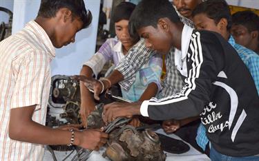 Teenagers at a Compassion center in India working on an engine