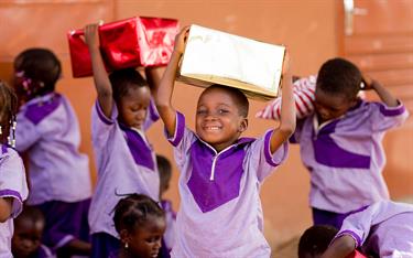 A child in Burkina Faso smiles as he receives a Christmas gift