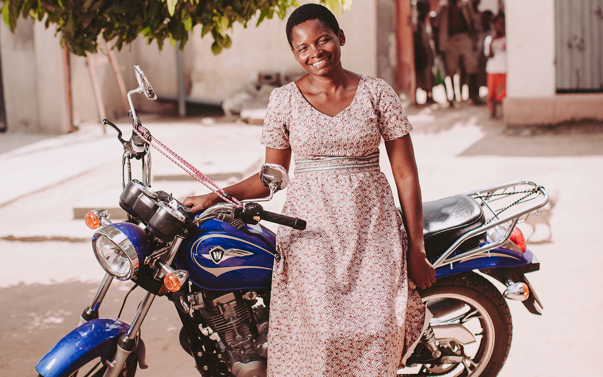 Komina stands in front of her motorbike