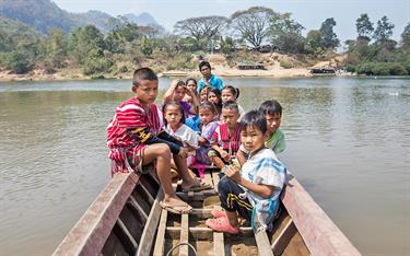 A large family and children sit in a small boat