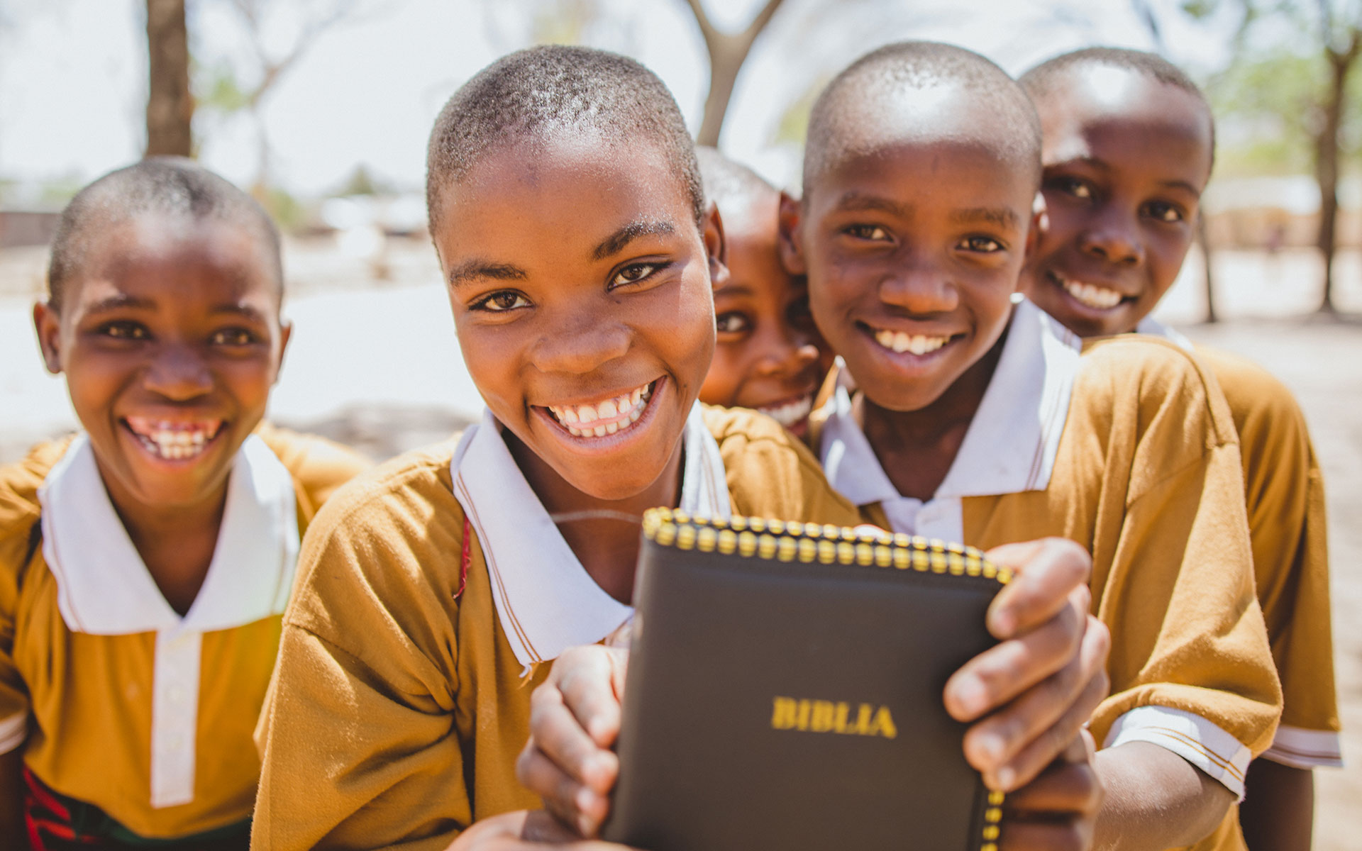Kids smile holding a Bible