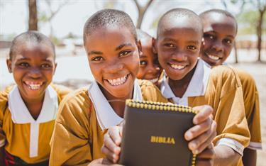 Kids smile holding a Bible
