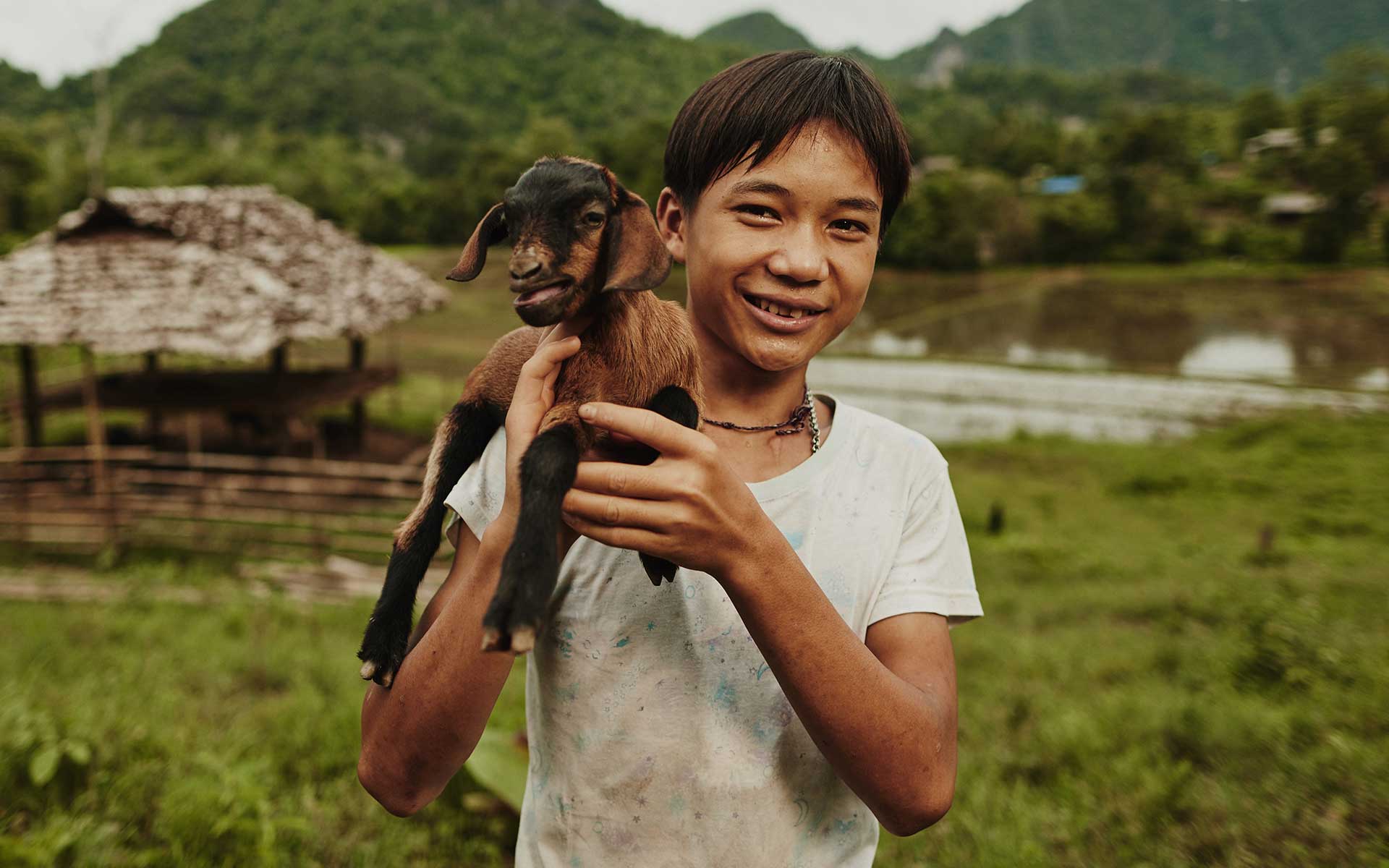 Treewit holding a goat near his home in Thailand