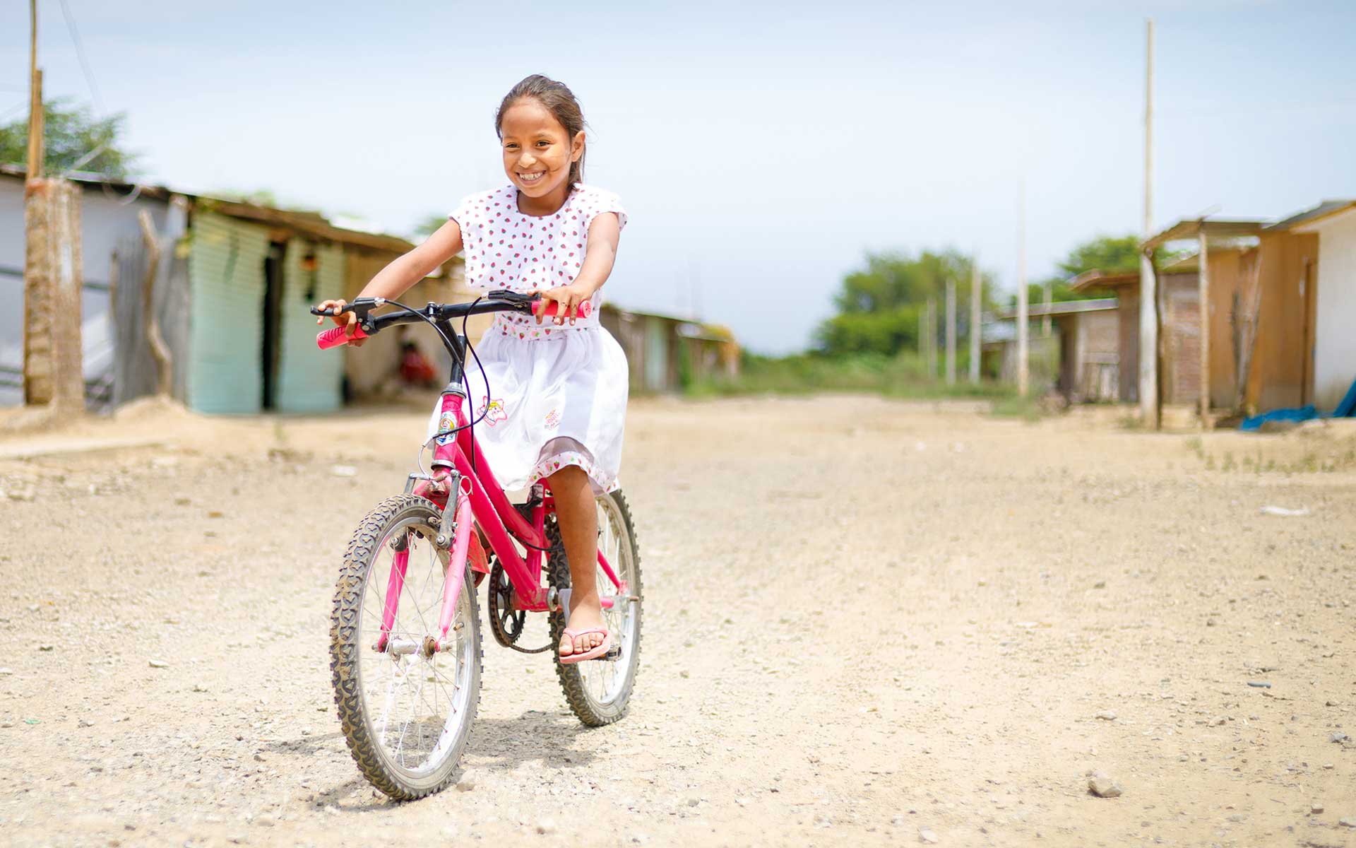 A young girl rides her bicycle through her neighborhood in Peru