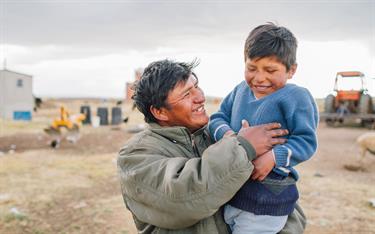 A Bolivian boy and his father laugh together.