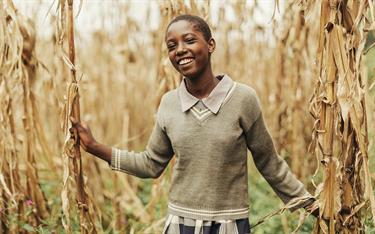 Tabitha, a 14-year-old from Kenya, stands in a cornfield