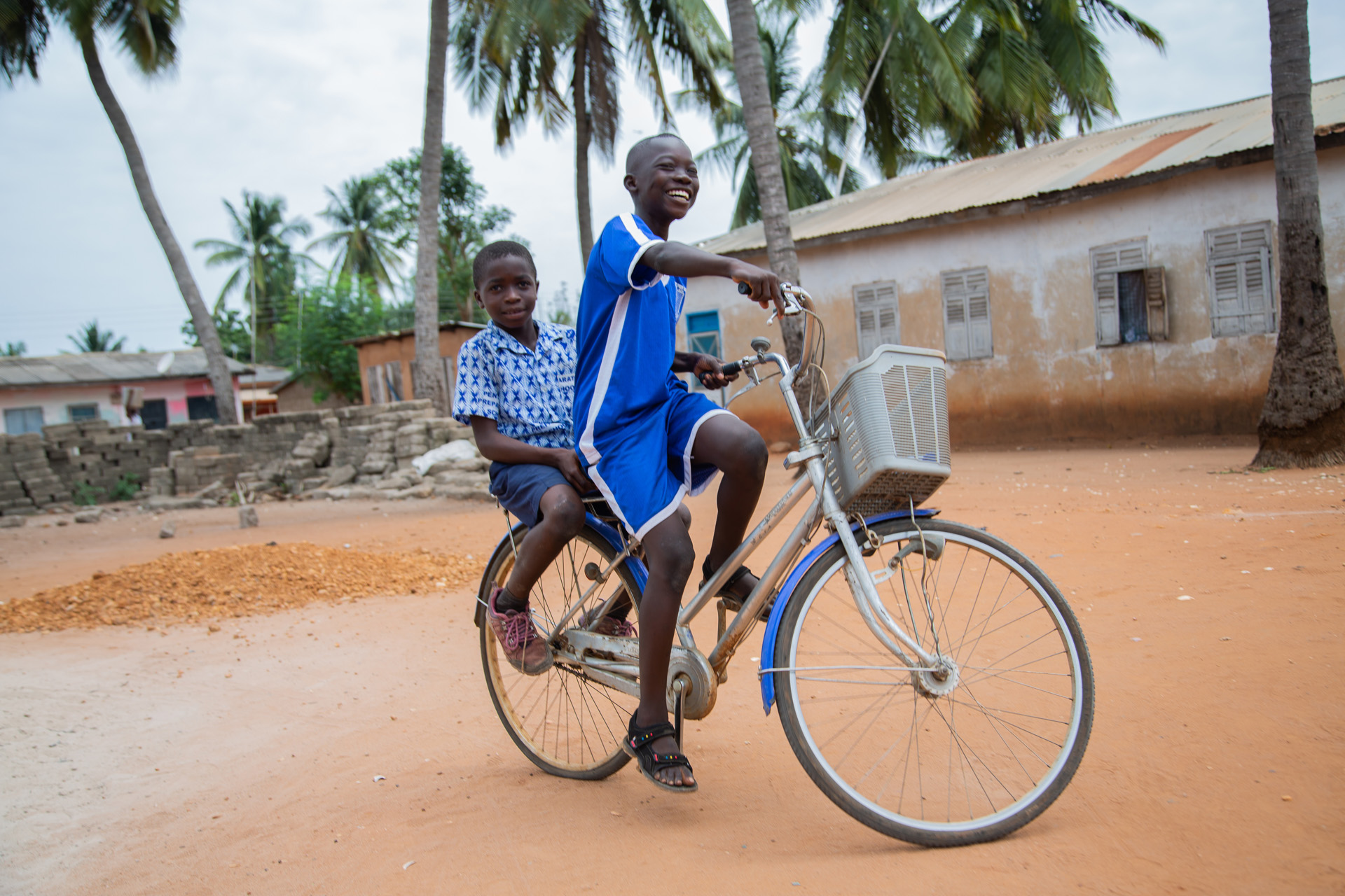 Boys in Ghana ride on a bicycle