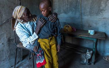 A young boy sits with his grandmother in their home in kenya