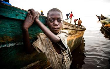 A boy plays near a boat in a Ugandan village